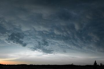Swirling Mammatus Clouds Over Forested Landscape at Sunset