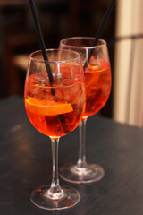 Aperol Spritz. Cold refreshing alcoholic cocktail Aperol Spritz. Cocktail close-up on a blurred background. Alcoholic drink in a glass with a straw. Traditional Italian alcoholic refreshing drink