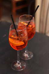 Aperol Spritz. Cold refreshing alcoholic cocktail Aperol Spritz. Cocktail close-up on a blurred background. Alcoholic drink in a glass with a straw. Traditional Italian alcoholic refreshing drink