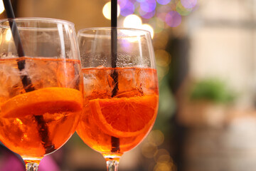 Aperol Spritz. Cold refreshing alcoholic cocktail Aperol Spritz. Cocktail close-up on a blurred background. Alcoholic drink in a glass with a straw. Traditional Italian alcoholic refreshing drink