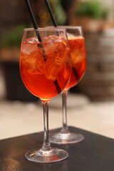 Aperol Spritz. Cold refreshing alcoholic cocktail Aperol Spritz. Cocktail close-up on a blurred background. Alcoholic drink in a glass with a straw. Traditional Italian alcoholic refreshing drink