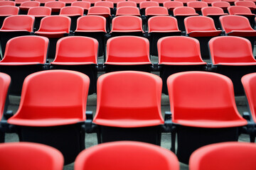 Obraz premium Seats of red tribune on sport stadium. empty outdoor arena. concept of fans. chairs for audience. Cultural environment concept. Color and symmetry. Empty seats. Modern stadium.