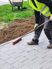 A municipal worker or cleaner, dressed in a green uniform, working or cleaning with a broom in the...