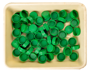 Plastic bottle caps in a flat plastic container.