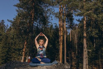 A woman meditating and practicing yoga on top of a rock at sunset, embracing wellness, mindfulness, and eco-friendly living