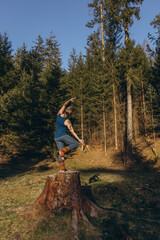 Fit sporty happy young woman wearing sportswear meditating doing yoga breathing stretching exercises standing in nature park outdoors in sunny morning. Authentic candid photo.