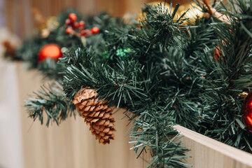 Christmas decoration close-up view, green artificial needles with cones and red balls