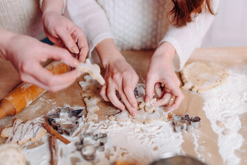 two friends, young women make Christmas gingerbreads from dough with metal forms