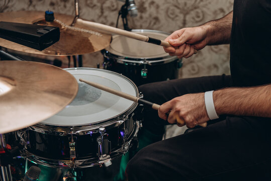 drummer plays drumset with wooden drum sticks, close-up view of hands