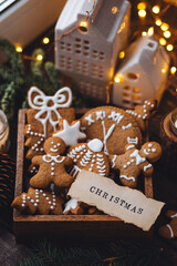 Concept of home christmas or new year celebration, family traditions. Assortment of gingerbread cookies with icing in a vintage wooden box on a window sill with atmospheric lights