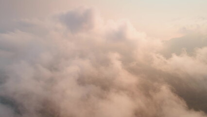 Capturing a breathtaking aerial view of fluffy cloudscapes during sunset, creating a serene atmosphere filled with warm pastel colors that evoke tranquility and beauty
