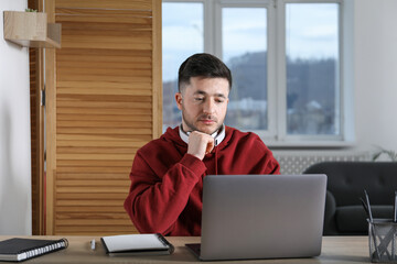 Man learning online using laptop at desk indoors. Self-study