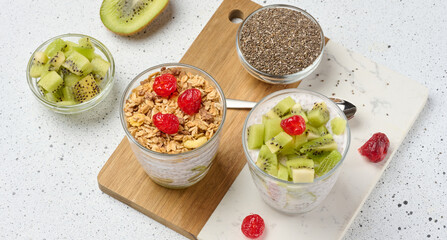 Yogurt and chia seed pudding in a glass, kiwi pieces. White table