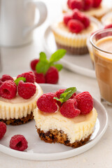 Classic New York cheesecakes in individual cups topped with fresh raspberry with a bite taken