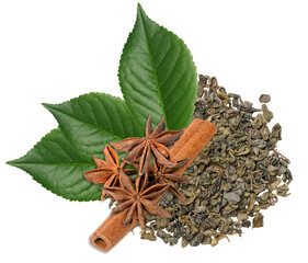 A pile of dry, rolled green tea leaves is arranged with three star anise, a cinnamon stick, and three green leaves, isolated background.