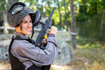 Portrait of pleased woman in uniform with paintball gun