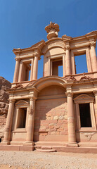 Obraz premium Historical architectural ruins against a clear blue sky, showcasing ancient sandstone structures and intricate designs, concept of travel agencies or tourism services