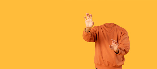 A headless figure wearing an orange sweatshirt gestures with hands in a vibrant yellow setting. This collage-style design emphasizes isolation with bright colors and empty space.