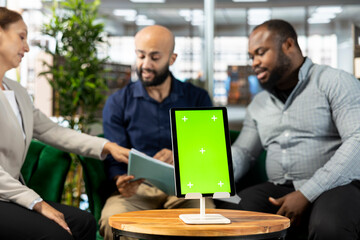 Isolated screen tablet next to workers looking over research documentation needed for finding business insights and finishing project task. Employees analyze data on mockup device and paperwork files