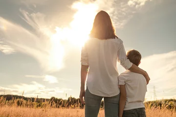 Fotobehang Mother and son spending time together in nature relaxing in a field looking at the sunset, Motherhood, and family parenting concept.   © kieferpix