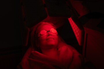 Woman receiving red light therapy treatment in wellness center