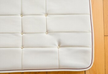 A close up of a white chair with red stitching.