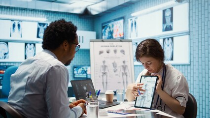 Healthcare provider presenting lab test results to a patient in cabinet, reviewing x ray and MRI...