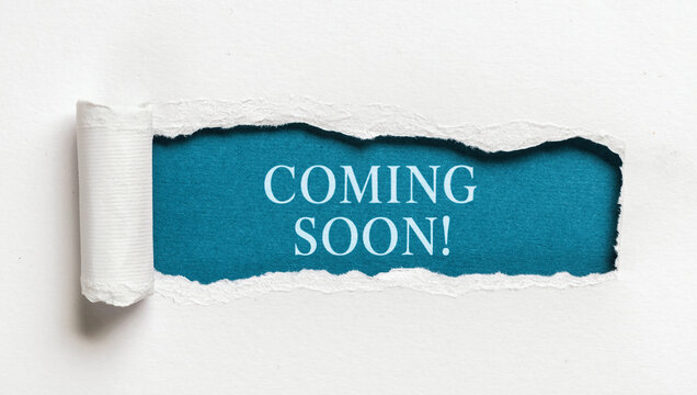 Text coming soon written on blue background behind ripped white paper creative announcement concept for marketing promotions and launch campaigns
