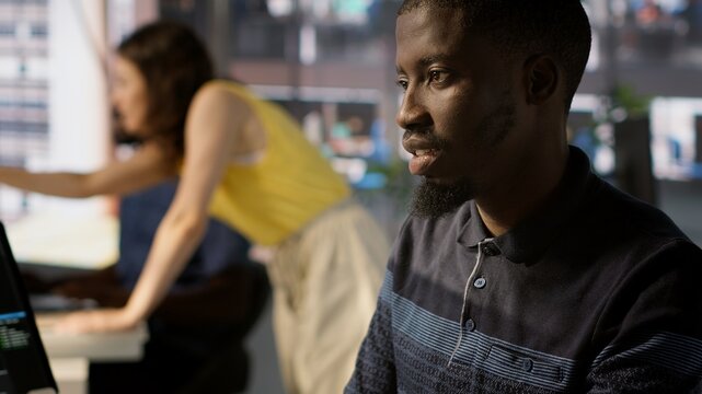 System administrator doing software quality assurance, checking source code on tablet. Close up of african american IT specialist at work inspecting coding on device, looking to fix errors, camera A