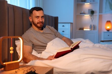 Fototapeta premium Young man with book in bed at home