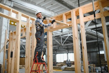 Construction of modular houses. Male construction worker in uniform and hard hat at construction...