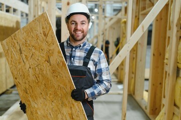 Portrait of a young carpenter worker in a helmet at the construction site of modular houses