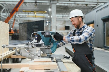 A worker uses a sawmill to process wood. Construction of modern modular houses.