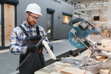 A worker uses a sawmill to process wood. Construction of modern modular houses.