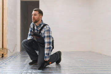 Service man instelling house heating system under the floor
