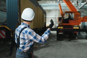 Foreman manages the loading of a prefabricated modular house to truck using walkie talkie