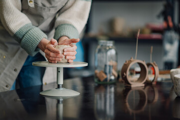 Potter kneading clay on pottery wheel in workshop