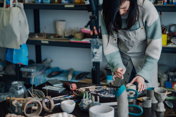 Ceramist sculpting clay in workshop with various tools