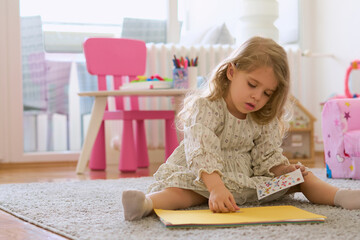 Portrait of 3 years old beautiful caucasian girl learning and doing activities, avoiding screen...