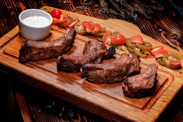 Top View of Appetizing Grilled Pork Ribs with Sauce, Jalapeсo Peppers and Cherry Tomatoes on Wooden Board with Irish Pub Logo, for Menu and Advertising.