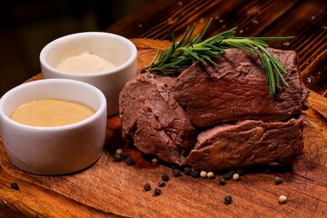 Appetizing Steak on Wooden Board with, Served with Two Sauces and Rosemary, Angled View, Ideal Photo for Pub Advertising, Menu, or Culinary Article.
