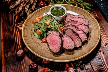 Appetizingly Sliced Steak with Pesto Sauce, Garnished with Greens and Cherry Tomatoes, on Stylish Plate and Wooden Table, Excellent Choice for Menu, Culinary Blog, and Gastronomic Advertising.