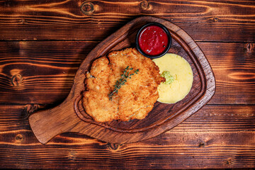 Overhead View of Golden Breaded Cutlet with Mashed Potatoes and Berry Sauce on Wooden Board, Dark Wood