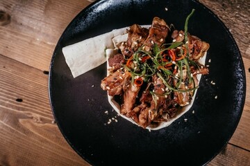Hearty Dish: Meat in Lavash with Vegetables and Spices on Black Plate, Rustic View on Wooden...