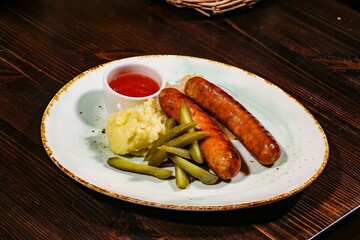 Juicy grilled sausages with mashed potatoes and pickles on rustic plate, top view