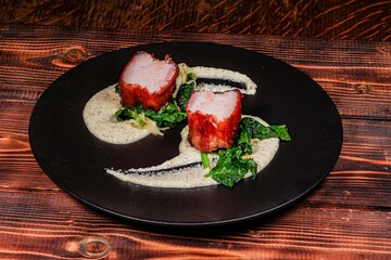 Exquisite Close-Up: Roasted Meat with Crispy Crust, Served on Delicate Cream with Vegetables on Black Plate, Demonstrating Gastronomic Perfection.