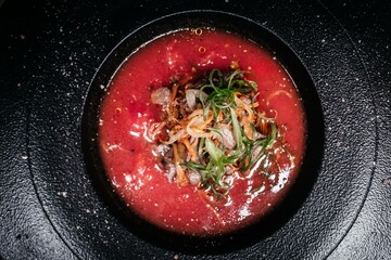 Culinary Masterpiece: Chilled Gazpacho with Exquisite Meat and Vegetable Composition, Emphasized by a Strict Black Background, Perfectly Reflecting Modern Gastronomy.