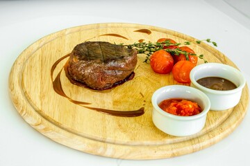 Appetizing Steak with Sauces, Thyme, and Roasted Tomatoes on Wooden Stand, Emphasizing Freshness and Quality of Ingredients.