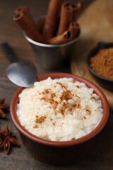 Tasty rice pudding with cinnamon served on wooden table, closeup