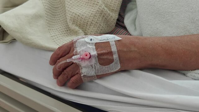Patient lying on hospital bed with IV drip.